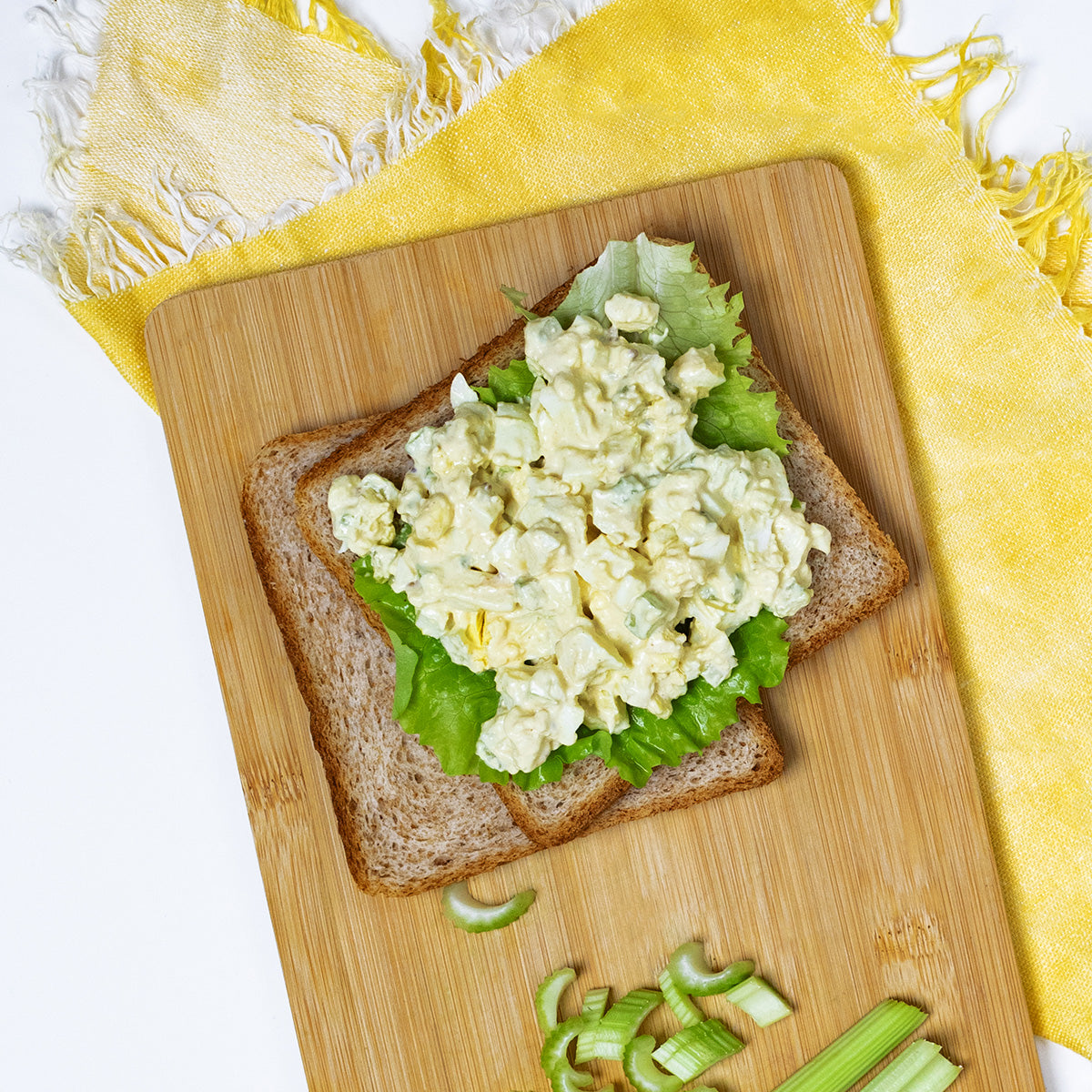 Open-face egg salad sandwich on wheat bread with lettuce, made with Zina's Fine Foods Classic Egg Salad