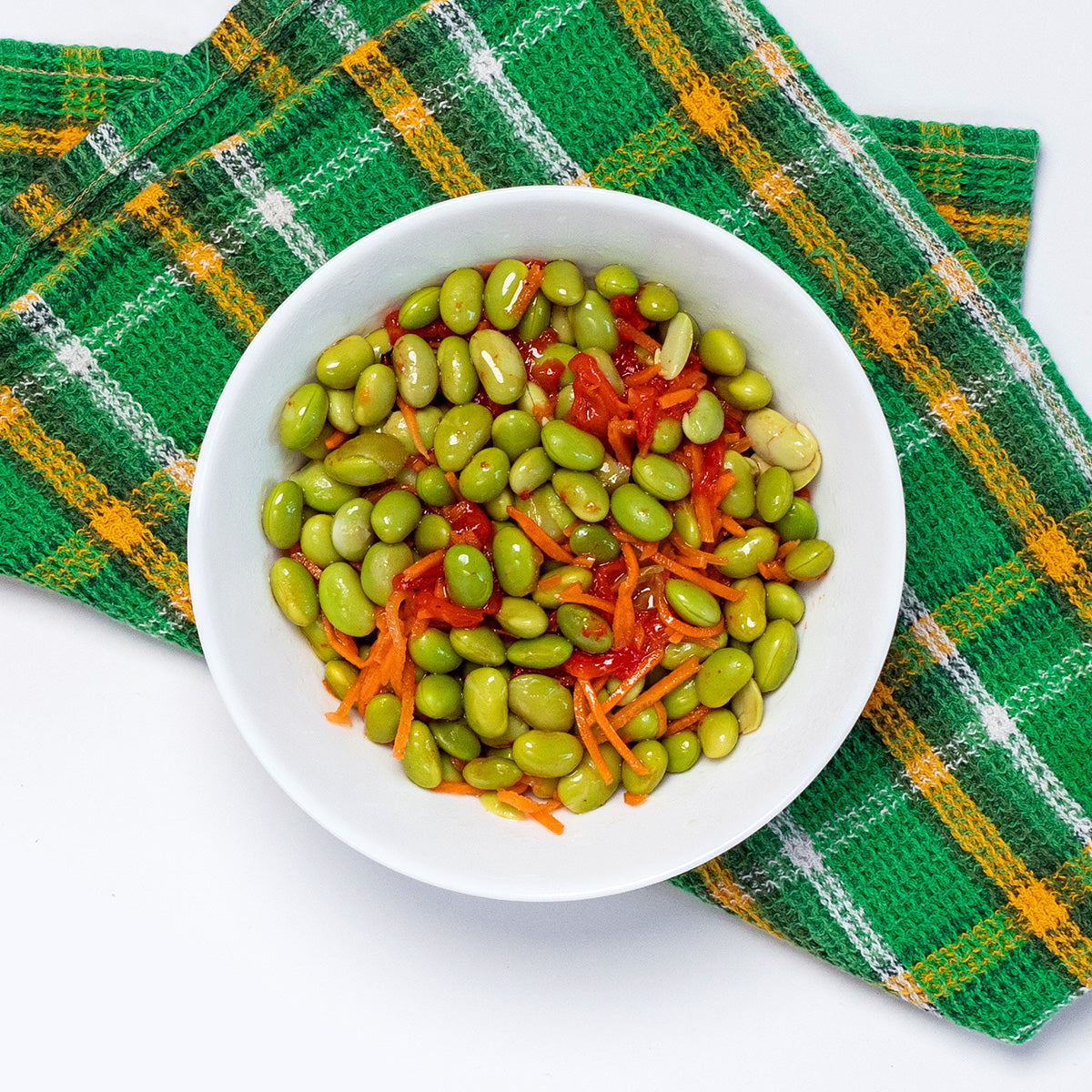 Edamame Salad with edamame, shredded carrots and roasted red peppers in a white bowl by Zina's Fine Foods