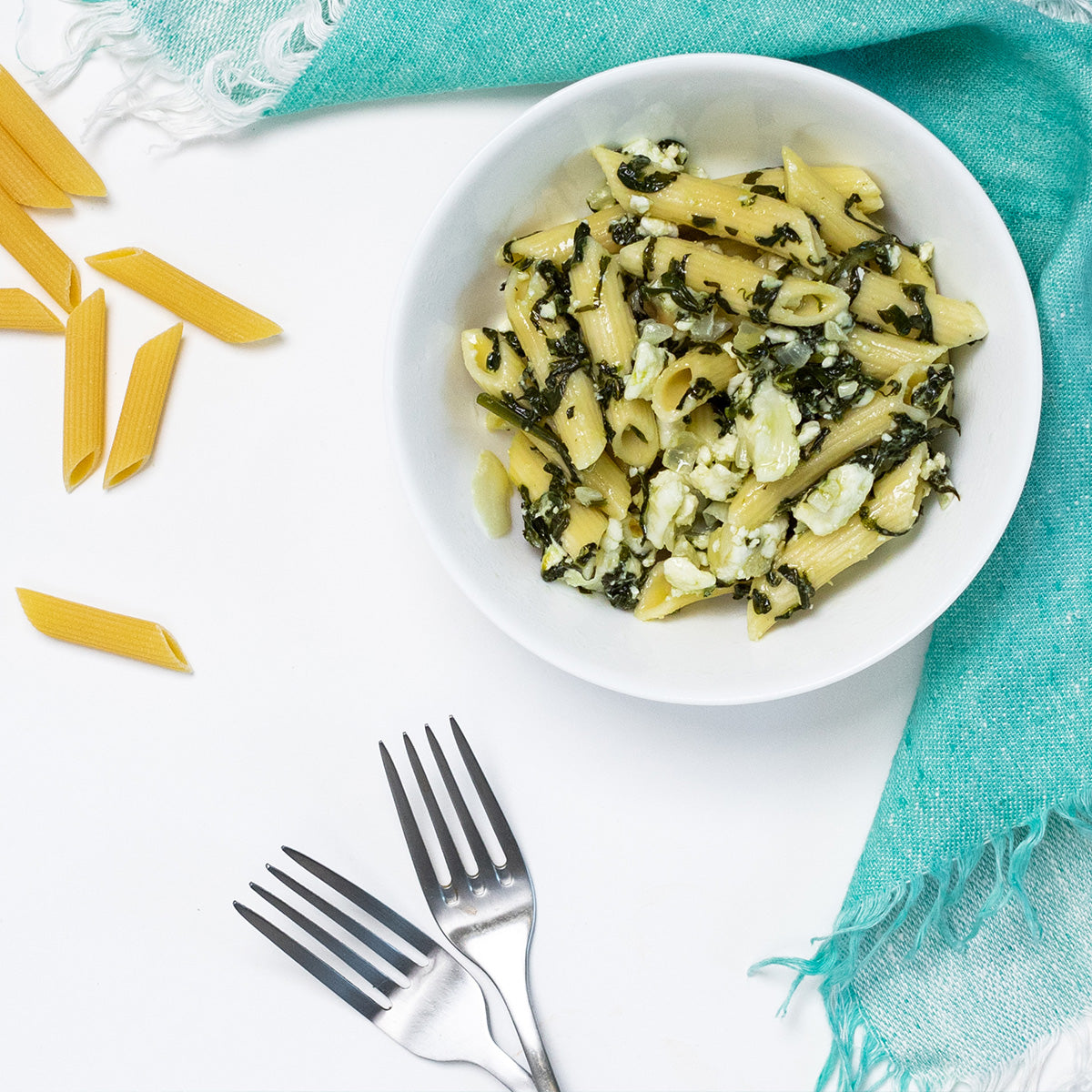 Penne Pasta with Spinach and Feta in a white bowl with penne, spinach and feta crumbles, by Zina's Fine Foods