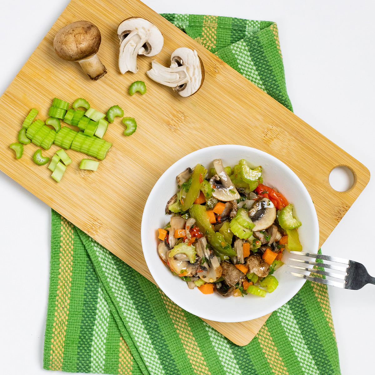 Zina's Fine Foods Portobello Mushroom Salad styled with fresh mushrooms and celery on a bamboo board