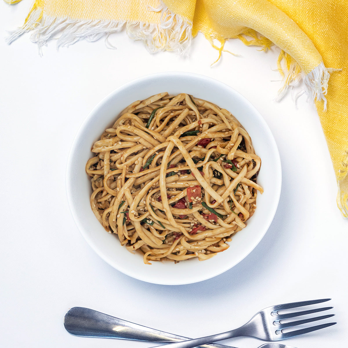 Sesame Noodle Salad with sesame seeds and chopped vegetables in a white bowl by Zina's Fine Foods