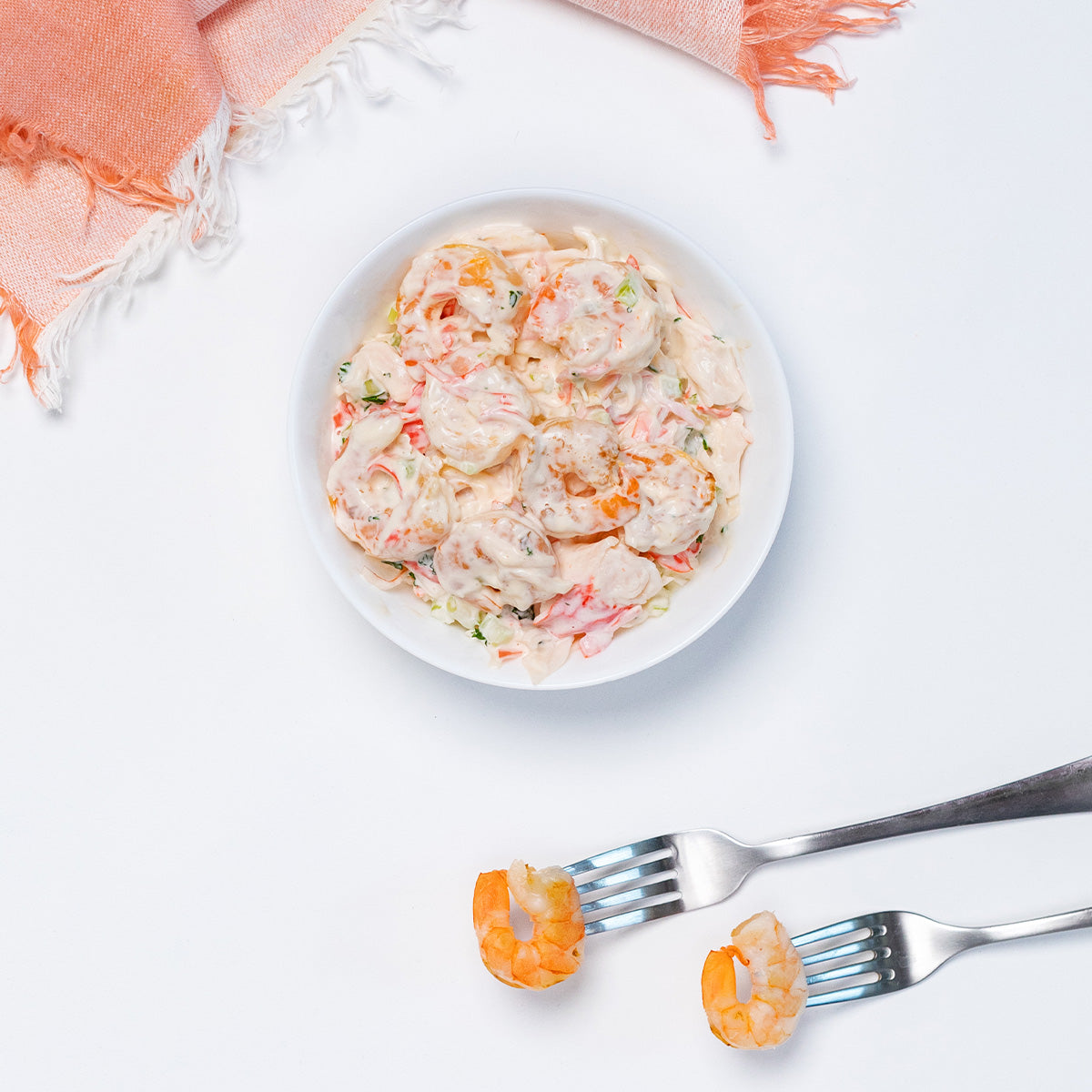 Zina's Fine Foods Shrimp Salad in a white bowl with whole shrimp shown on forks in the foreground