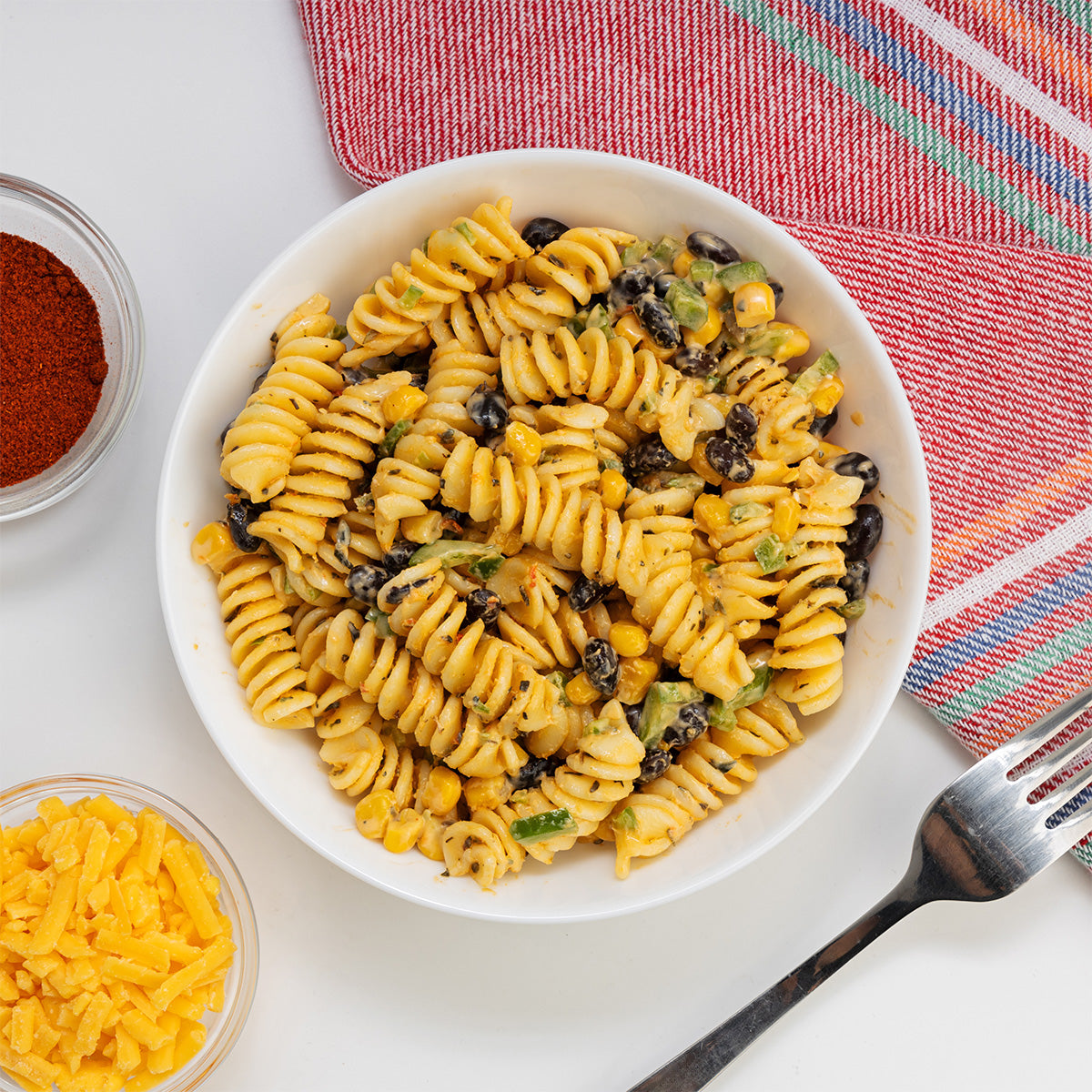Southwest Taco Pasta Salad with rotini, black beans, corn and southwest seasoning in a white bowl by Zina's Fine Foods
