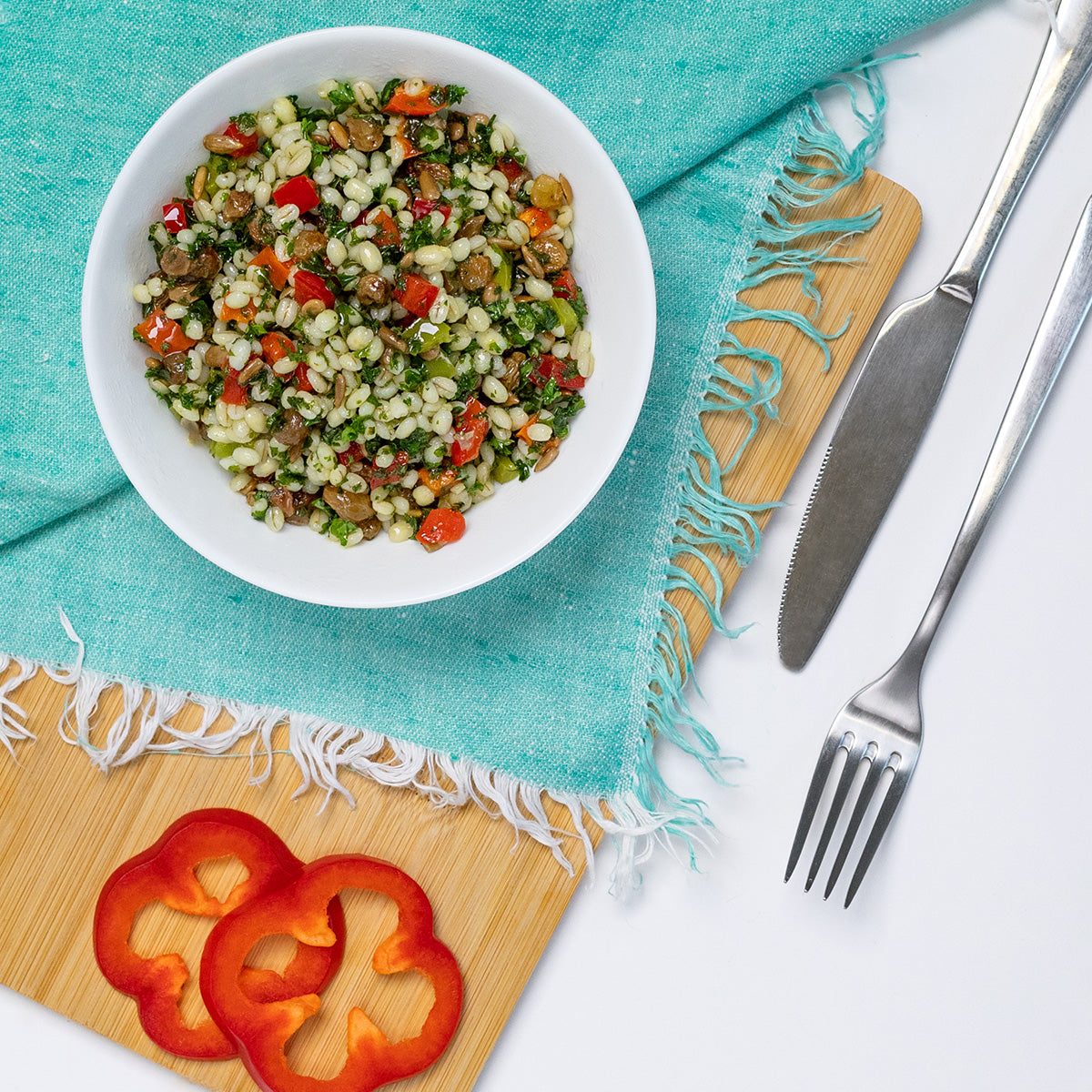 Zina's Fine Foods Wheatberry Salad styled with red bell pepper slices on a bamboo cutting board