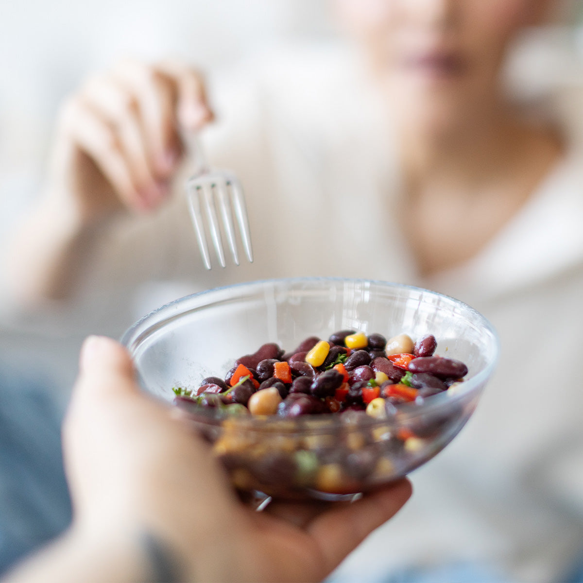 Close-up of Zina's Fine Foods Black Bean Salad in a clear bowl with corn and red pepper
